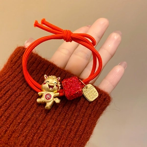 Détail de l'élastique rouge avec pendentif cochon doré et cube de cristal brillant