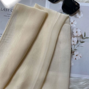 Detail of beige silk scarf with elegant folds and soft texture on white plush background
