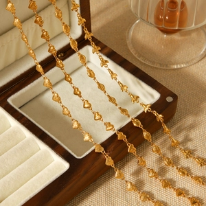 Golden heart link necklace draped on a wooden jewelry box with high polish finish