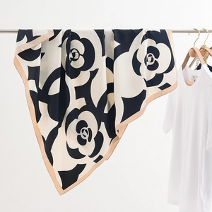 Dettaglio di un foulard in seta con stampa a camelia e bordi beige eleganti e ampi