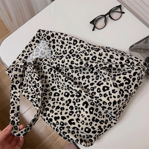 Dettaglio di borsa tote in tela leopardata con tracolla larga su sfondo bianco