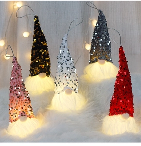 Macro detail of LED glowing Christmas gnomes with sequin hats on soft white fur backdrop