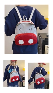 Detail of cute red and grey cow backpack with 3D ears on a toddler's back