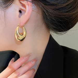 Close-up of a minimalist chunky gold U-shaped earring on model with polished finish