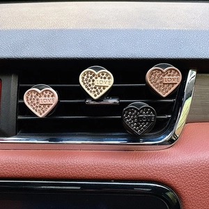Detail of four heart-shaped rhinestone car vent clips with LOVE text in various colors