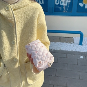 Close-up of pink quilted makeup bag featuring heart patterns and zipper closure