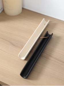 Primer plano de porta inciensos cerámicos minimalistas en negro mate y blanco crema suave