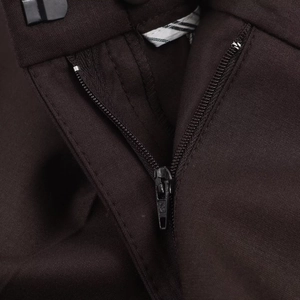 Détail macro de la fermeture éclair en métal noir et coutures du pantalon marron foncé
