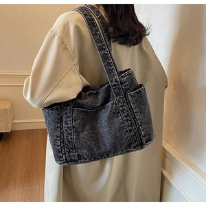 Detail of dark gray denim tote bag showing white contrast stitching and side pockets