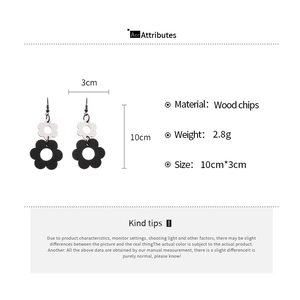 Detailed view of bohemian layered wood flower earrings with white and black petals