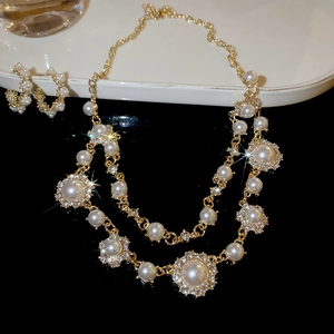 Detail of double-layer gold necklace set with diamonds and pearls on a sleek display