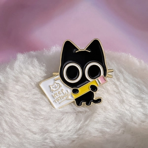 Cute black cat enamel pin holding a pencil with Keep Trying text on plush background