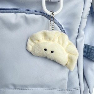 Cute dumpling plush keychain on blue backpack with soft cream fabric and metal chain