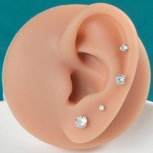 Close-up of four stainless steel cubic zirconia stud earrings on a silicone ear model