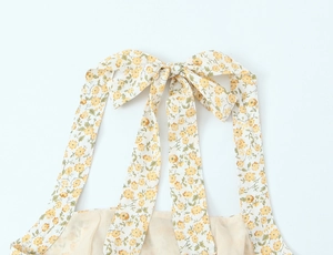 Détail d'une robe d'été à fleurs avec un nœud jaune délicat noué au niveau du décolleté