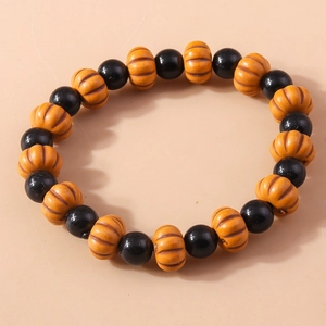 Macro shot of Halloween beaded bracelet featuring orange pumpkin and black skull charms