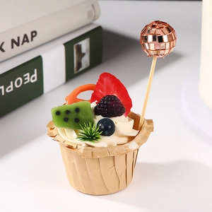 Detail showing a rose gold disco ball cake topper on a realistic fruit cupcake decor