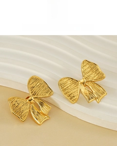 Détail de boucles d'oreilles nœud plaquées or 18 carats avec surface en métal brossé