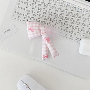 Detail view of a pink quilted bow pouch resting on a white laptop for daily storage