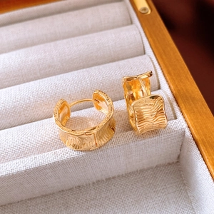 Detailed macro view of 18K gold plated wide hoop earrings with wave texture in a jewelry box