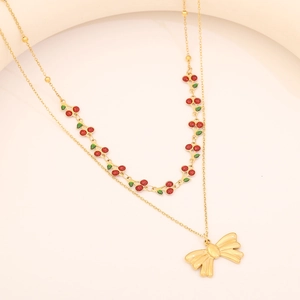 Détail d'un collier doré à double rangée avec pendentifs cerises rouges et nœud