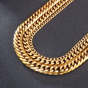 Detailed view of three polished golden stainless steel Cuban link chains on black background
