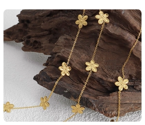 Close-up of golden daisy flower link chain jewelry on textured dark wood background
