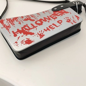 Detail of creative cleaver bag featuring red Halloween help text and bloody handprint