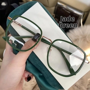 Detail view of emerald green square frames with gold metal temples and soft velvet bag