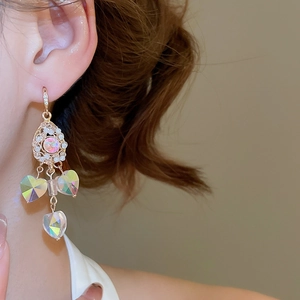 Close-up of elegant crystal drop earrings with heart charms worn by a female model