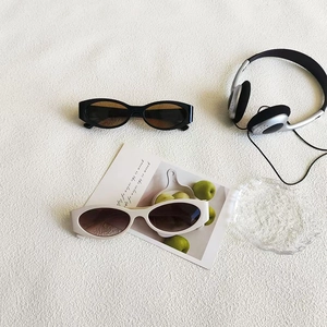 Chic retro oval cat-eye sunglasses in black and beige displayed on a white fabric background