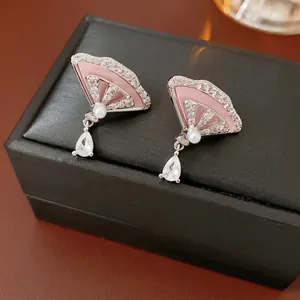 Pink fan-shaped drop earrings with zircon embellishments and white pearls on a jewelry box
