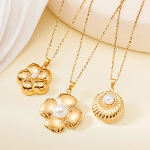 Three vintage gold stainless steel necklaces with pearl pendants on a soft fabric background