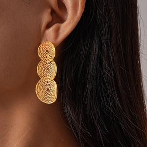 Detail of gold hollow mesh geometric earrings worn by model for elegant metal style