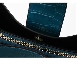 Detail view of teal crocodile embossed leather with gold zipper and magnetic closure