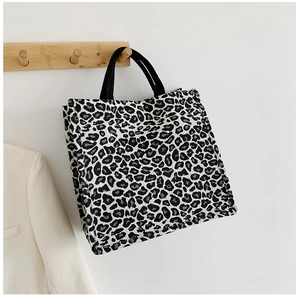 Detailed texture of leopard print tote bag hanging on wooden hook with canvas material