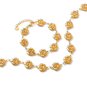 Ensemble collier et bracelet fleur dorés en acier inoxydable sur fond blanc élégant