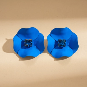 Close-up of matte blue flower earrings with square navy gemstone center inlay
