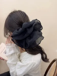 Detail of a large black double-layered pleated mesh scrunchie for an elegant ponytail look