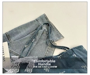 Detail of blue denim tote bag featuring white bow prints and delicate lace edge trim