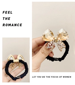 Detail of crystal bow hair tie with champagne gemstone and black elastic cord