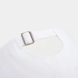Close-up of adjustable bronze buckle and cotton fabric on white baseball cap