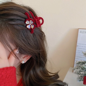 Macro shot of a red velvet four-leaf clover hair claw clip with rhinestones on hair