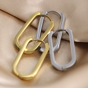 U-shaped 18K gold and silver stainless steel earrings on champagne silk background