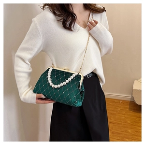 Detail of dark green velvet shell bag with diamond patterns and pearl handle