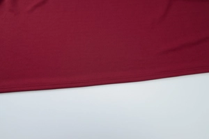 Detailed close-up of dark red knitted dress hem showing professional stitching and fabric