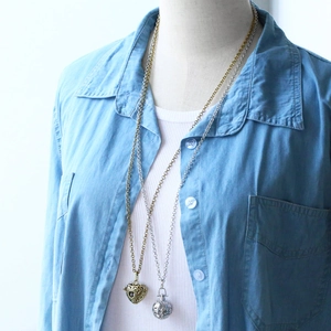 Close-up of vintage hollow aromatherapy locket necklaces shown on a model