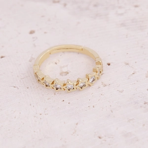 Detail of gold star ring with micro-pave white zircon stones on natural stone surface