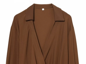 Détail de l'élégant col en V et du drapé plissé sur le devant d'une chemise marron