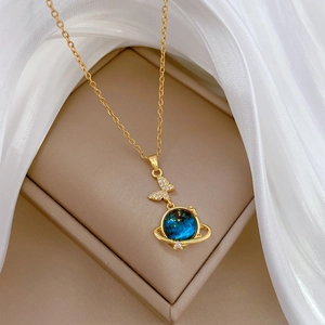 Close-up of butterfly and blue star planet pendant with crystals on gold chain